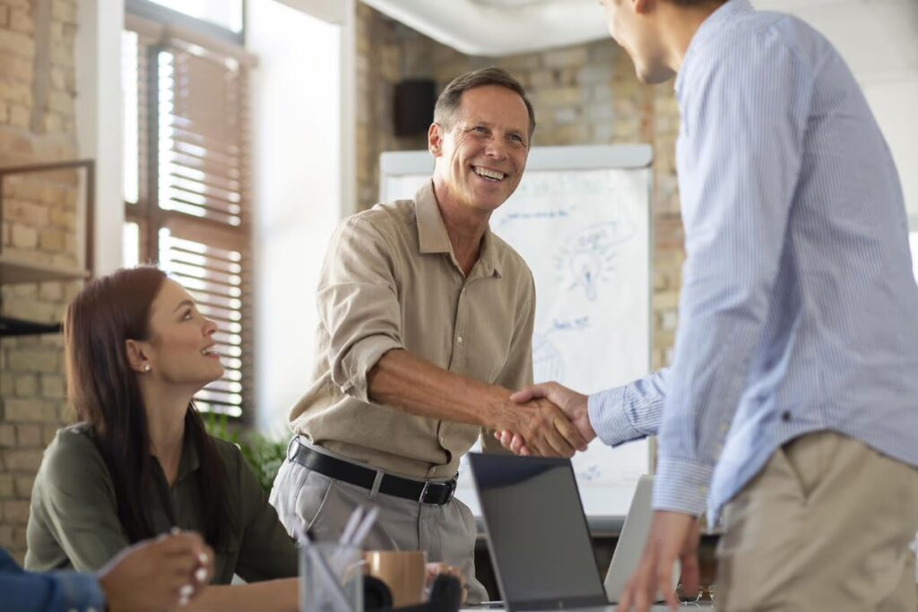 Profissionais de customer experience apertam as mãos em reunião